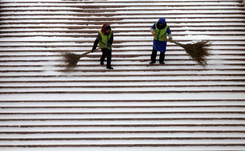 12月23日,园林工人冒雪在威海市幸福公园的台阶上清理积雪。受冷空气影响,山东省威海市12月22日夜间开始降雪,气温明显下降。新华社发(于启波 摄)