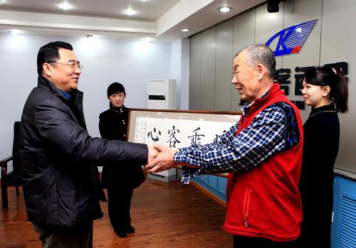 1月18日,年过七旬的锦州市书法家刘凤吉(右一)为沈阳铁路局锦州客运段送来写“情暖乘客心”的横匾,感谢K7320次列车乘务员在旅途中对他的照顾。锦州客运段在备战春运中,努力提升服务质量,对独行老人进行重点照顾,并设专人进行到站提醒,送老人下车。新华社发(高锦旭摄)