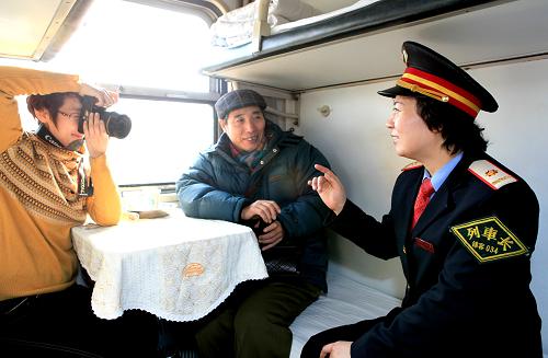 1月19日,锦州客运段7591次列车列车长在向旅客介绍沿途旅游风光,她的熟练介绍令旅客十分佩服,拿起相机拍照留念。沈阳铁路局锦州客运段在备战春运中,在列车员中开展熟知沿途风光景区、熟知沿途车站到发时刻、熟知重点旅客到站需求的“三熟知”培训,不断提高服务水平。新华社发(高锦旭摄)