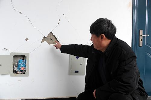1月23日,辽宁省辽阳市灯塔市柳条寨镇政府工作人员向记者介绍被地震震裂的政府房屋墙壁。