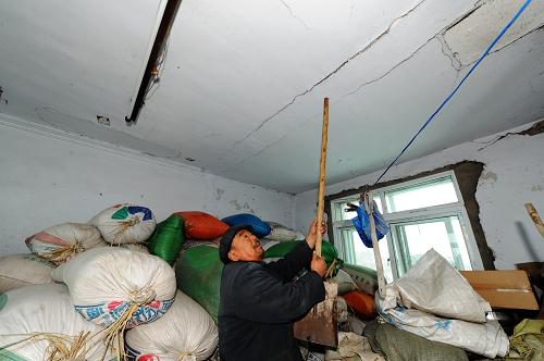 1月23日,在辽宁省辽阳市灯塔市柳条寨镇蒿子屯村,一位村民指示被地震震裂的房屋天花板。新华社记者 杨青 摄