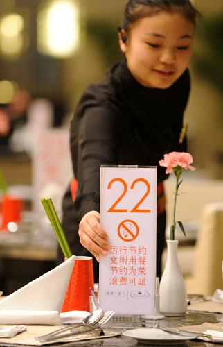 1月24日,青岛海景花园大酒店,一名员工在更换印有“厉行节约、文明用餐”提示的桌号牌。新华社记者 李紫恒 摄
