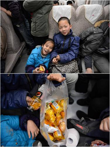 10岁的小康(左)和11岁的哥哥小周在北京读小学,这次他们跟着妈妈一起回家。由于没有买到坐票,只好带着小板凳坐在过道上,幸运的是有好心人让了个座位给他们。他们的晚饭是一袋小蛋糕,价格17元。不过两个孩子因为回家太兴奋,都顾不上吃晚饭了(2月1日摄)。新华社记者 周密摄