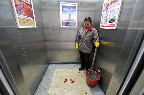 2月10日,在江西省南昌市滨江豪园小区一栋单元楼的电梯内,清洁工在清扫擦洗楼道内燃放爆竹后留下的残渣。新华社记者 彭昭之 摄