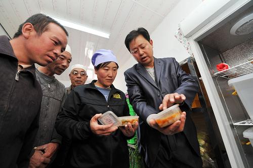 3月20日,在宁夏回族自治区西吉县吉强镇夏寨小学的库房内,工作人员(右)向学生家长介绍学校每天留底的免费午餐样本。近日,记者在宁夏西海固地区走访时发现,当地许多农村学校为了确保免费午餐的食品安全,让免费午餐更加透明化,邀请家长代表介入免费午餐的制作过程,确保孩子们吃得安全、舒心。 新华社记者 彭昭之 摄