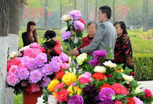 一名小贩在洛阳市某公园内售卖牡丹绢花(2013年4月3日摄)。近年来,“牡丹花都”河南省洛阳市重视牡丹产业的开发与推广,精心打造“牡丹经济”,形成了完整的牡丹产业链条。以牡丹为主题的各类艺术品、 深加工产品,已成为洛阳旅游的新名片。新华社记者 王颂 摄