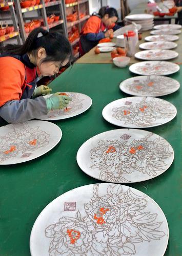 在洛阳市一家瓷器厂的车间内,技术工人在为“洛阳三彩牡丹瓷画”原坯上釉(2012年10月29日摄)。新华社记者 王颂 摄