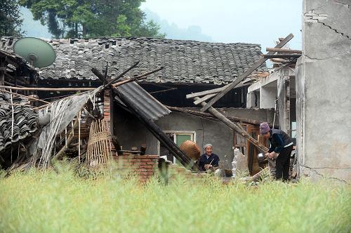 4月28日,在芦山县宝盛乡玉溪村,村民李元何(左)和妻子在自己损毁的房屋内寻找生活用品。当日是四川省芦山“4·20”7.0级强烈地震后的第九天。新华社记者 金良快 摄