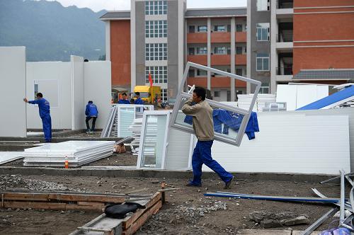 4月30日,在芦山县太平镇中学操场,施工人员在搭建板房学校。“五一”小长假期间,工人加班加点为芦山县太平镇中学建设板房教室,以保证师生们尽快复课。据统计,芦山地震已累计造成雅安市357所学校受损,全市329所中小学、16万余名在校中小学生受到影响停课。在确保学生安全前提下,雅安市中小学校克服各种困难,采取多种形式复课。截至4月29日,雅安全市中小学中已有297所复课。新华社记者 金良快 摄