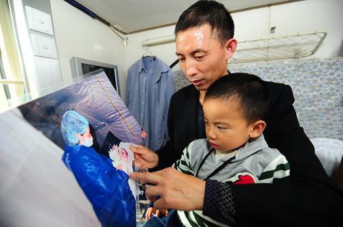 5月10日,在前往上海的列车上,父亲张贵昌给小弘扬看“兵妈妈”给他接生时的照片,讲述他出生时的情形。