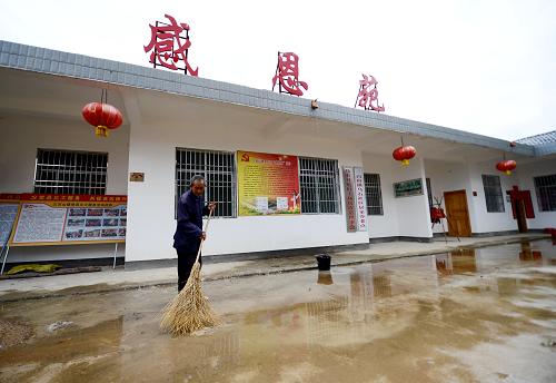 在安远县三百山镇乌石村感恩苑,73岁的特困老人谢家辉在清扫地面积水(5月9日摄)。新华社记者 周科摄