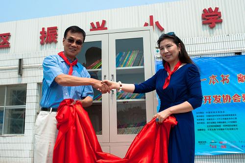6月13日,在北京市海淀区民办打工子弟学校振兴小学,中国扶贫开发协会副会长谷永江(左)与“爱心书架”活动主要捐助方负责人共同为“爱心书架”揭幕。当日,由中国扶贫开发协会主办的“爱心书架”活动正式启动。主题为“捐一本书,献一份爱,圆一个梦”的“爱心书架”活动是中国扶贫开发协会文化扶贫的重要品牌项目,根据全国上百个贫困地区近万名小学生的调查问卷,动员社会力量为孩子们捐赠“孩子们最想要的礼物”。活动计划第一批在江西、海南等贫困地区的县级小学内设立100个“爱心书架”,并开展读后感比赛和朗诵比赛等促读活动。新华社记者刘金海摄