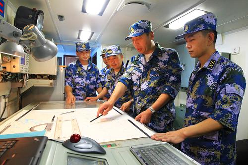 8月22日,海军舰艇编队指挥员魏钢少将(右二)在青岛舰海图室布署编队航行计划。新华社记者 查春明 摄
