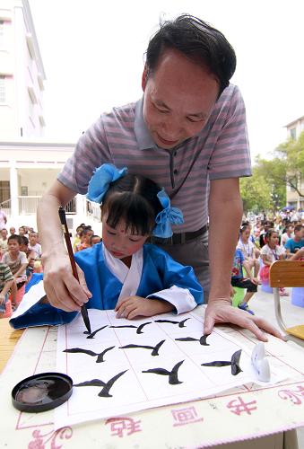 9月13日,在柳城县大埔镇第一小学,当地一名书法家手把手教学生写“人”字。当日,广西首所中国书法家协会“兰亭学校”——柳城县大埔镇第一小学为300多名一年级新生举行了“开笔礼”。活动旨在弘扬中华民族优良的传统文化,让学生迈好学习的第一步。“开笔礼”是中国传统文化求学四大礼之一,俗称“开笔破蒙”,是一种少儿识字习礼的启蒙教育形式。新华社发(邓克轶 摄)