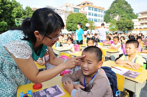 9月13日,广西靖西县实验小学教师在“开笔礼”仪式上为一年级新生点朱砂。 新华社发(赵京武 摄)
