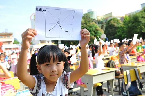 9月13日,广西靖西县实验小学一年级新生在“开笔礼”仪式上展示自己书写的“人”字。新华社发(赵京武 摄)