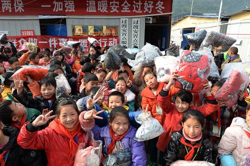12月5日,在四川省雅安市宝兴县灵关镇赵家坝集中过渡安置点,宝兴县灵关镇中心小学的学生展示领取到的棉衣。新华社发(李向雨 摄)