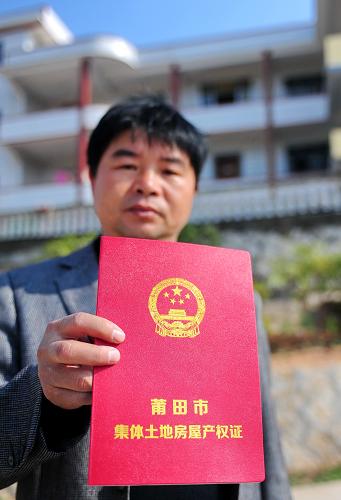 华亭镇涧口村村民卢国山在家门前展示他的集体土地房屋产权证(12月4日摄)。福建莆田华亭镇涧口村村民卢国山近日拿到了一本崭新的“集体土地房屋产权证”,他高兴地对记者说:“房子有了‘身份证’,白纸黑字,确认是我家的财产,心里很踏实。”“这本证是土地证和房产证‘两证合一’。”卢国山说,产权证上确认他一家6口宅基地使用权面积160平方米,房屋产权面积494平方米,房屋性质为私有,加盖了区国土局和住建局的公章。目前,莆田正在全市16个村试点农地、农房确权发证工作,涉及1.46万多户7.21万多村民,第二批3个乡镇和30个村的确权发证工作也即将开始,涉及2.1万户近10万村民。新华社记者 林善传 摄
