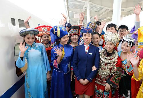 12月30日,在南宁火车站,身着民族盛装的乘客在搭乘动车前和乘务员合影。新华社记者 周华 摄