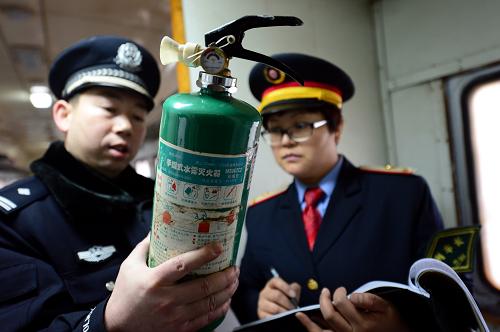 1月26日,7516次列车长刘莉(右)和乘警长张皓在检查车厢内灭火装置。新华社记者 张锰 摄