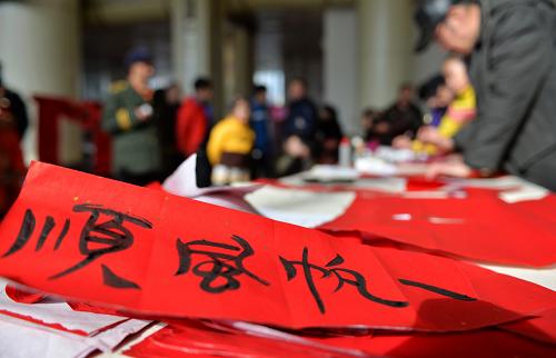 1月27日,在兰州火车站候车厅,书法爱好者们为旅客书写新春对联。新华社记者 陈斌 摄