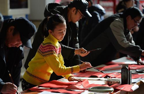 1月27日,在兰州火车站候车厅,书法爱好者们为旅客书写新春对联。新华社记者 陈斌 摄