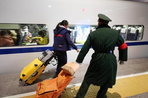 1月30日,武警浙江总队直属支队的武警战士在杭州铁路东站帮旅客拿行李。新华社发(郭广杰 摄)