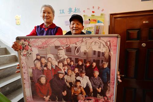 2月27日,两位居民展示自己所住单元的“全家福”。从2013年9月以来,甘肃省酒泉市肃州区北新街社区尝试在辖区21栋廉租房的部分单元内开展“单元一家亲”活动。在社区工作人员的指导和帮助下,廉租房小区的居民结合自己所住的单元特点,分别创建起文明之家、光荣之家、互助之家等10个特色主题单元,居民们通过公选楼院长、开辟议事栏、设计楼道文化墙,安排卫生值日表和张贴住户“全家福”合影照等方式加强沟通交流,将所居住的单元打造成一个充满创意和温馨的大家庭,不仅美化了楼道环境,也增强了居民的归属感、认同感和凝聚力。新华社记者 陈斌 摄