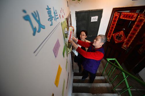 2月27日,北新街社区副主任张玉莲(左)和居民一起整理楼道内的爱心服务袋。新华社记者 陈斌 摄