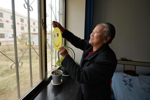 2月27日,廉租房小区“光荣之家”单元居民崔桂芳在自己家里悬挂代表邻里互助的笑脸标志。新华社记者 陈斌 摄