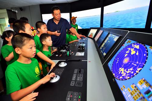 8月7日,在天津海运职业学院的仿真航海模拟器训练中心,学生们在教师的指导下体验船舶驾驶舱模拟环境。 当日,2013年“少年派的职业技能体验之旅”夏令营开营,30名参加夏令营的天津中小学生将在天津海河教育园区的职业院校校园参观现代图书馆、生产实训场地、3D打印机等,并体验消防公安工作、学习安全保护知识,了解职业教育。 新华社发(游思行 摄)