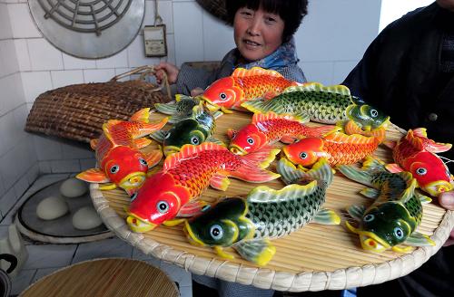 1月15日,山东省莱州市朱桥镇贾家村村民孙雪堂展示她制作的鱼形花饽饽,这种花饽饽蕴含“年年有余”的含义。新华社记者 徐速绘 摄