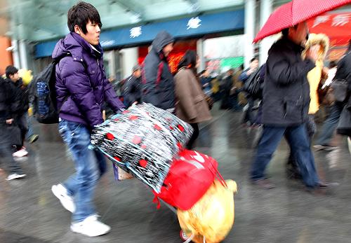 1月18日,步履匆匆的旅客冒着风雨行走在上海火车站外的广场上。 2011年全国春运19日将拉开大幕,目前上海地区学生流、民工流和探亲流三股客流汇聚态势初步显现,上海铁路局客票预售已达428.5万张,比去年同期增长27.8%,上海地区的春运大幕即将开启。 新华社记者陈飞摄
