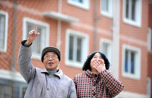 江西九江市花甲老人刘长智夫妇在螺狮山小区欣喜地看着自己的房子。螺狮山小区属于九江集中建设的保障性住房小区,这里三分之一的住户享受了廉租房政策(2010年12月19日摄)。江西省自2007年开展保障性安居工程建设以来,4年已累计解决64万户家庭住房困难问题,惠及人口近200万。2011年,江西省将新增6.59亿元用于保障性住房建设,进一步改善困难群众居住条件。新华社记者 周科 摄