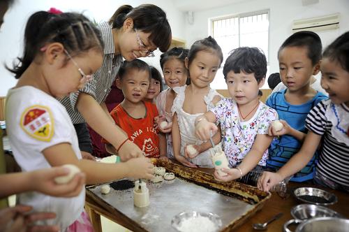 9月9日,浙江省东阳市妇联幼儿园的老师在指导小朋友做月饼。 新华社发(包康轩 摄)