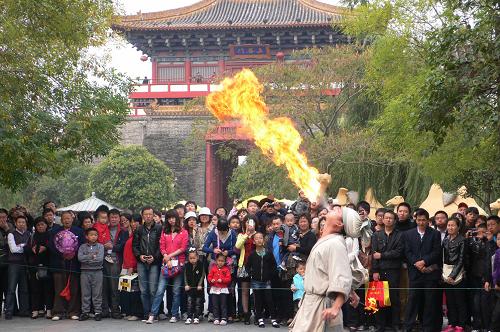 10月2日,众多游客在河南开封市清明上河园观看气功喷火表演。当日是国庆长假第二天,河南开封市公园景点里来自四面八方的游客络绎不绝,丰富多彩的民俗文化表演让游人大饱眼福。新华社 发