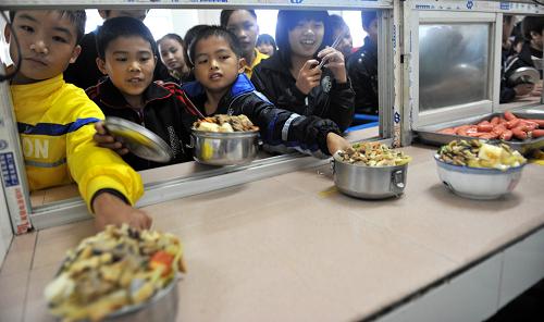广西忻城县城关镇中学的学生在学校食堂领取免费“营养午餐”(2011年10月28日摄)。 据悉,广西日前在国家确定的农村义务教育学生“营养午餐”29个试点县的基础上,新增11个区级试点县,这意味着广西将有40个县区、116万农村中小学生能够享受到“营养午餐”的待遇。 新华社发(樊绍光 摄)