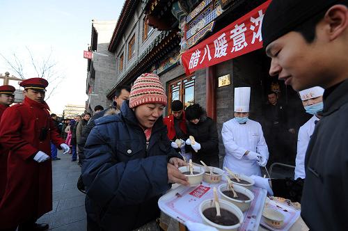 1月1日,北京全聚德前门老店的员工穿着传统中式服装在前门步行街向市民游客送腊八粥。当日,2012年的新年与农历腊八节“喜相逢”。全国各地佛教寺院、药堂和一些饭店、社区免费向群众发放腊八粥。新华社记者 张旭 摄
