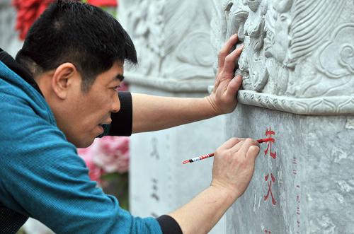 4月2日,在北京八宝山人民公墓,一位市民在描红墓碑上的字。 中国传统节日清明临近,许多人选择在清明期间以各种方式祭奠逝者、缅怀先烈。 新华社记者李文摄