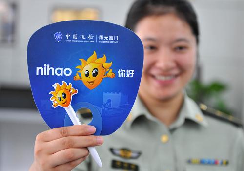 8月19日,在南京市公安局出入境受理大厅,南京港边检站一女兵展示饰有中国边检服务品牌形象“天天”图案的扇子、圆珠笔等纪念品,准备向旅客免费发放。新华社记者 孙参 摄