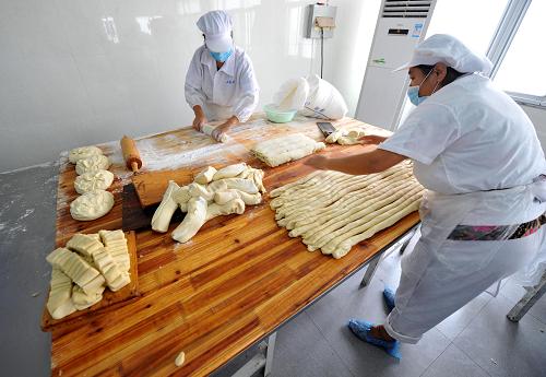 8月24日,南京老字号“小苏州”食品公司月饼生产车间的员工在卫生洁净的台面上擀皮。新华社记者 孙参 摄