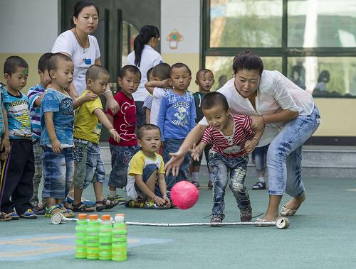 8月24日,幼儿园大三班的同学在操场上开展课外活动,和老师一起玩“保龄球”。新华社记者 陈诚 摄