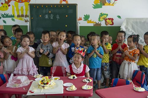 8月24日,幼儿园大二班的同学在教室给同学高仪歌(前)唱生日歌,庆祝她5岁生日。新华社记者 陈诚 摄