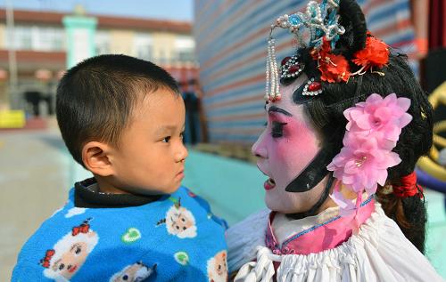 “庄户剧团”乐乡村 11月24日,村民苗学燕的儿子有点认不出化了装的妈妈。 农忙已过,山东邹平县西黄村的“庄户剧团”又开始忙碌起来,十里八乡的村庄都纷纷邀请她们去演出。西黄村业余剧团1998年正式成立,由村民们自发、自愿结合,不计任何报酬。十几年来,业余剧团的演职人员不断变化,但为村民义务演出的传统和对民间戏曲的喜爱一直没改变。现在,西黄村业余剧团的成员们已经整理、编排传统剧目37出,每年为村民演出40余场次。 据山东省文化部门统计,山东目前有农村民办剧团5200个,这些“庄户剧团”根植乡村大地,丰富繁荣了农村文化生活。 新华社记者 朱峥摄