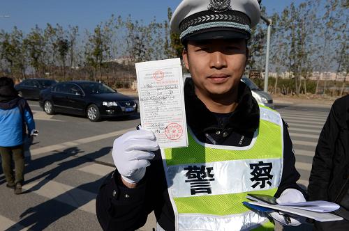 1月1日,南昌市公安交通管理局红谷滩大队的交警在展示给闯红灯的车辆开具的罚单。新华社记者 宋振平 摄