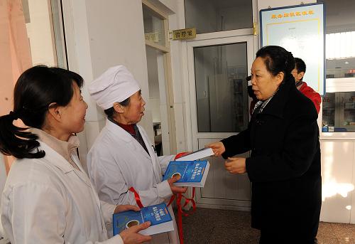 1月18日,惠民医药卫生事业发展基金会理事长惠鲁生(右一)向延庆井庄镇张伍堡社区卫生服务站的医生赠送《中成药临床合理使用读本》。新华社记者 何俊昌 摄