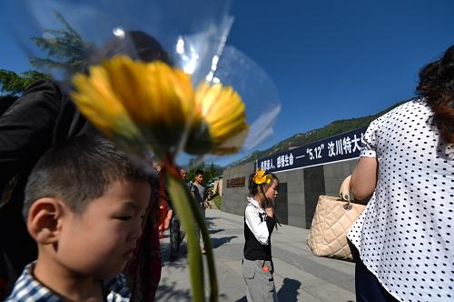 5月12日,前来祭奠逝者的群众手持鲜花。当日是汶川地震5周年纪念日,当地群众和遇难者家属在汶川县映秀镇遇难者公墓祭奠逝者,寄托哀思。新华社记者 白禹 摄