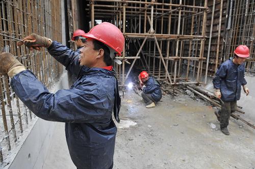 6月22日,工人冒着细雨在工地现场紧张施工。新华社记者 鲁鹏 摄