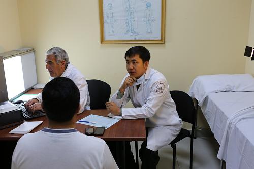 9月13日,中国人民解放军第七批援厄医疗队高长明主治医师(右)在位于首都基多的厄瓜多尔三军总医院接诊。新华社记者 郝云甫 摄