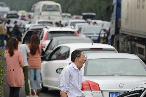 10月1日,在成雅高速拥堵路段,人们在等待通车。当日是今年“十一”黄金周高速公路小客车免费通行第一天,四川境内成雅、雅西、成绵等多条高速拥堵。四川省高速交警预计出行高峰时间为今明两天,返程高峰为6至7日,车流将集中在成雅、雅西、成绵、成渝、成乐等高速路段。新华社记者 李桥桥 摄
